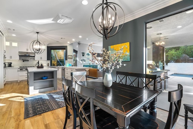 dining space featuring ornamental molding, light wood-type flooring, and an inviting chandelier