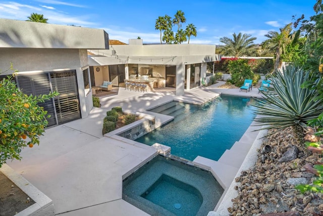 view of swimming pool with area for grilling, a patio area, an outdoor bar, and an in ground hot tub