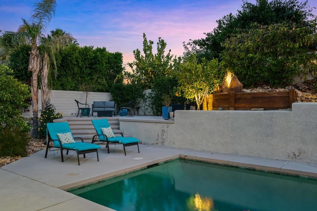 pool at dusk with outdoor lounge area and a patio area