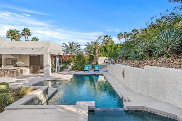 view of pool with a patio, exterior bar, and area for grilling