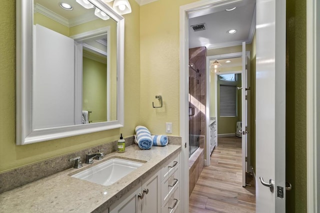 bathroom with vanity, hardwood / wood-style floors, ornamental molding, and a shower