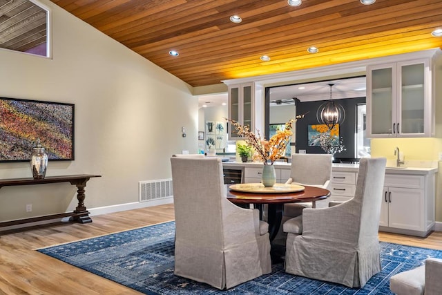 dining room with wood-type flooring, ornamental molding, wooden ceiling, and a chandelier