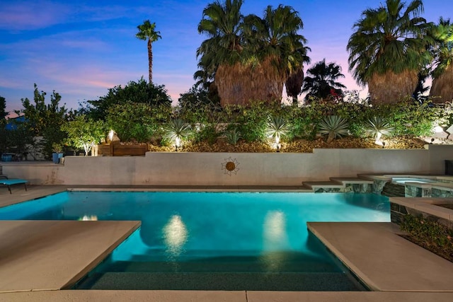 pool at dusk with an in ground hot tub