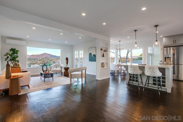 living room with a mountain view, dark hardwood / wood-style floors, and a wall unit AC