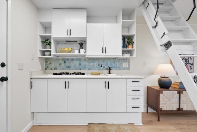 kitchen with sink, white cabinets, light wood-type flooring, and white gas cooktop