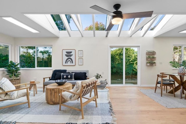 living room featuring a wealth of natural light, light hardwood / wood-style flooring, and a skylight