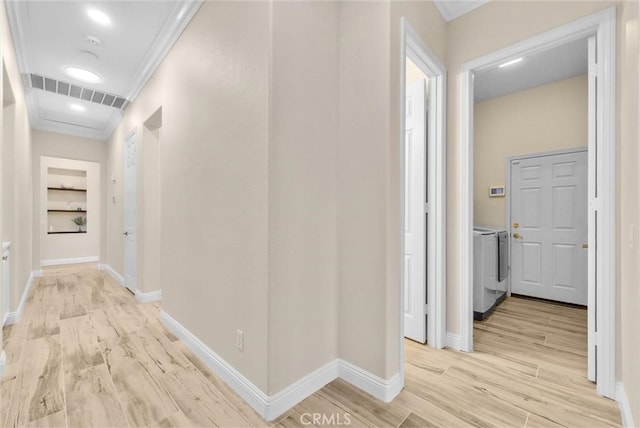 hall with separate washer and dryer, ornamental molding, and light wood-type flooring