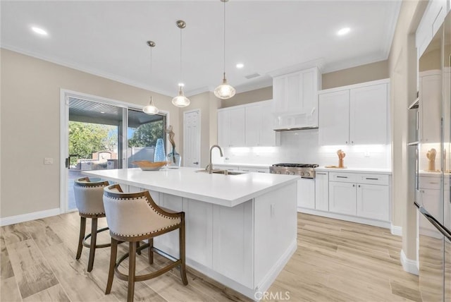 kitchen with white cabinetry, sink, decorative light fixtures, and a center island with sink