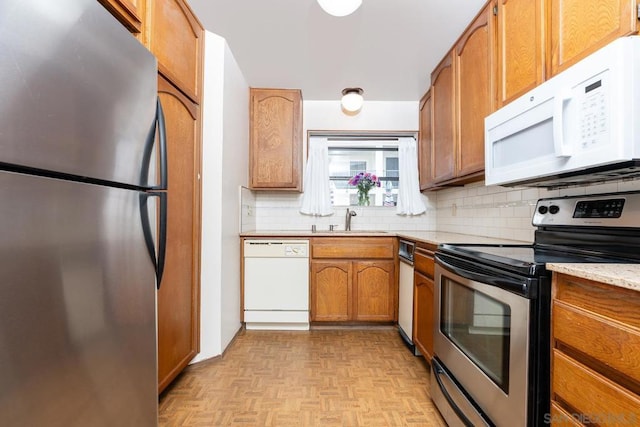 kitchen featuring light parquet flooring, appliances with stainless steel finishes, sink, and backsplash