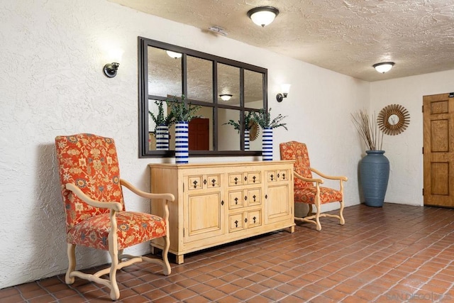 sitting room with dark tile patterned flooring and a textured ceiling