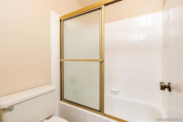 bathroom with toilet and combined bath / shower with glass door