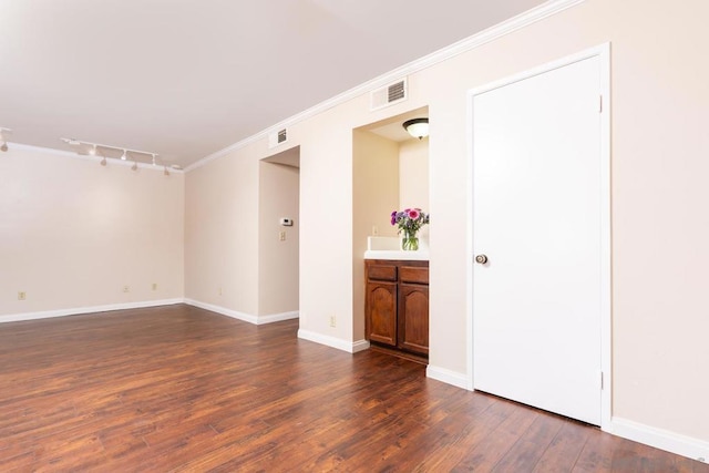 empty room with crown molding, dark hardwood / wood-style floors, and rail lighting