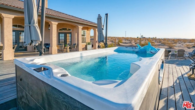 view of swimming pool with french doors and a deck