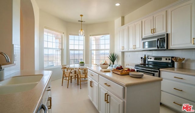 kitchen featuring sink, a center island, appliances with stainless steel finishes, pendant lighting, and white cabinets