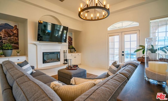 living room with a notable chandelier, french doors, and a raised ceiling