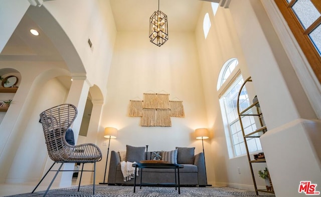 sitting room with a towering ceiling and a chandelier