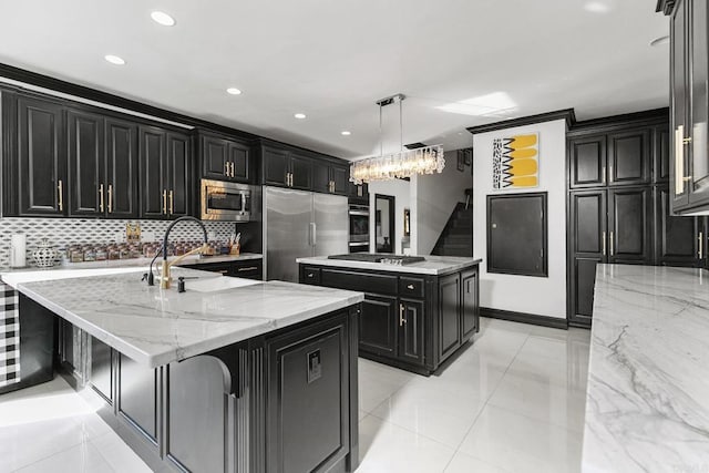 kitchen featuring built in appliances, light stone counters, decorative light fixtures, and a large island with sink