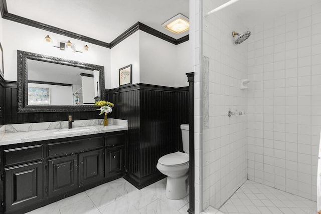 bathroom featuring ornamental molding, toilet, vanity, and a tile shower