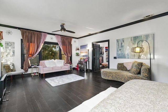 bedroom featuring wood-type flooring, a spacious closet, ornamental molding, a closet, and ceiling fan