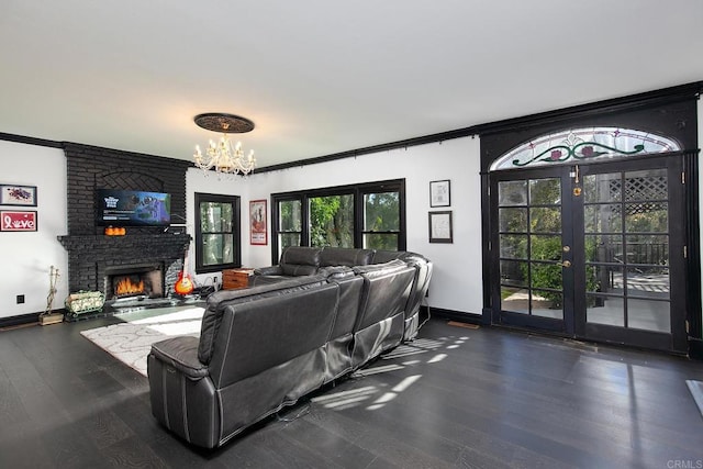 living room with french doors, a chandelier, ornamental molding, dark hardwood / wood-style flooring, and a fireplace