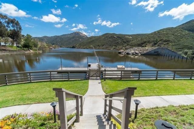 exterior space with a water and mountain view and a lawn