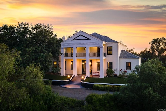 view of front of home featuring a balcony and a yard