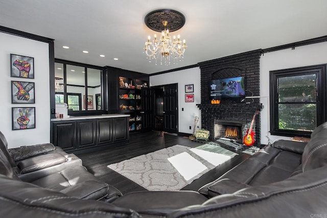 living room featuring crown molding, a chandelier, dark wood-type flooring, and a brick fireplace