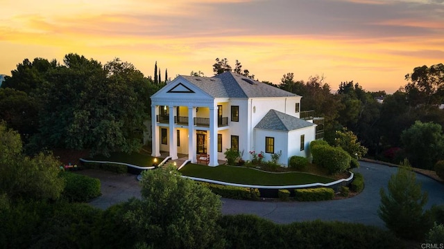 neoclassical home featuring a yard and a balcony