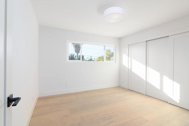 unfurnished bedroom with a closet and light wood-type flooring