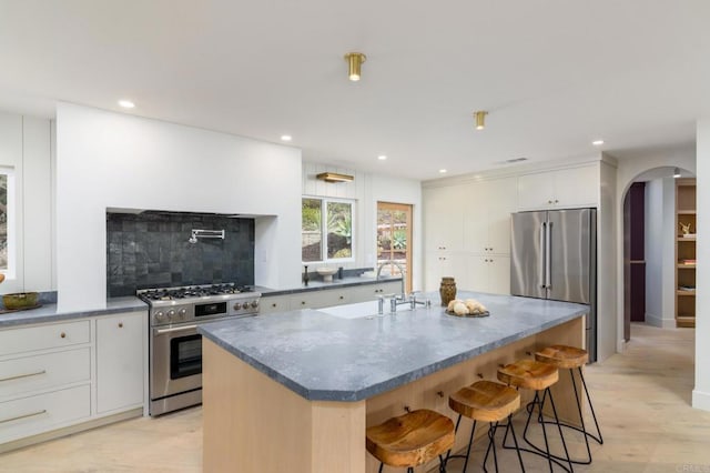 kitchen featuring white cabinetry, a breakfast bar, stainless steel appliances, and a center island