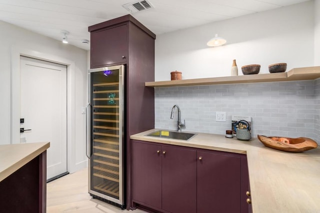 kitchen featuring tasteful backsplash, sink, beverage cooler, and light hardwood / wood-style floors