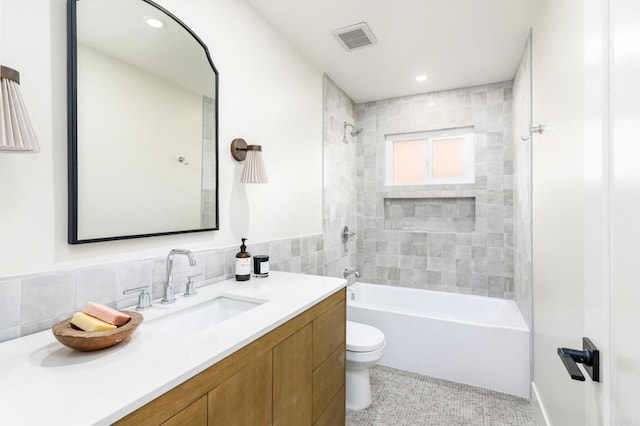 full bathroom featuring tile patterned floors, toilet, tile walls, vanity, and tiled shower / bath combo