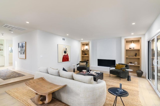 living room with light hardwood / wood-style flooring and built in features