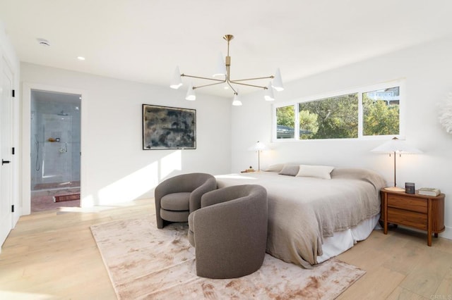 bedroom with ensuite bath, light hardwood / wood-style floors, and a notable chandelier