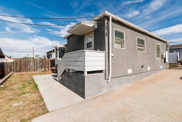 view of property exterior with crawl space, fence, and stucco siding