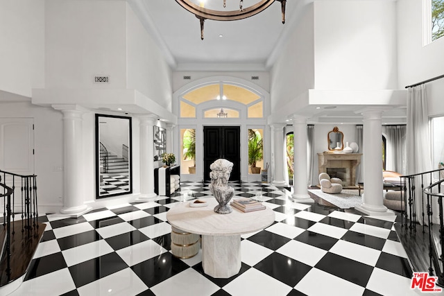 entrance foyer featuring decorative columns, crown molding, and a high ceiling