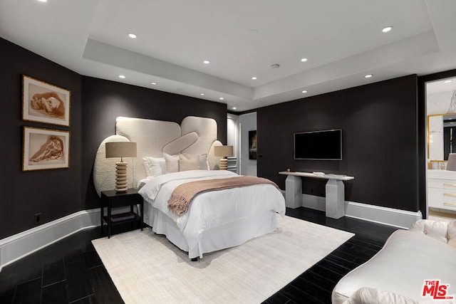 bedroom featuring a raised ceiling and dark hardwood / wood-style floors