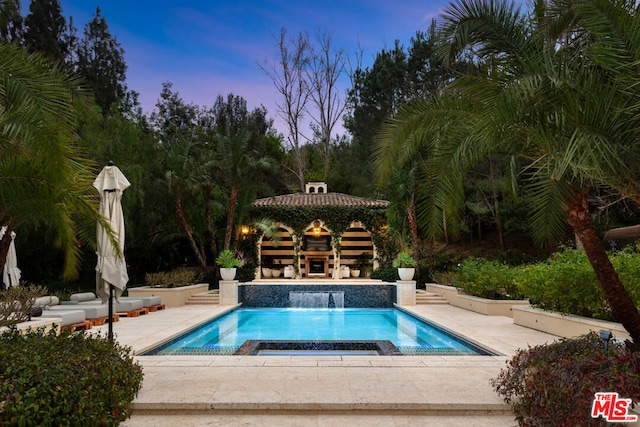 pool at dusk featuring a gazebo