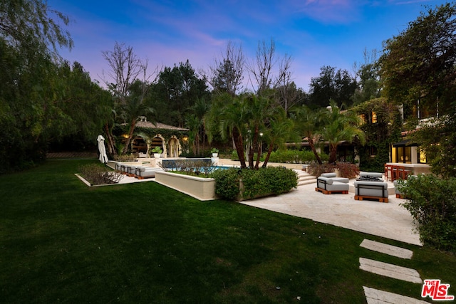 yard at dusk featuring a patio area