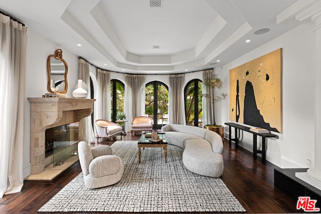 living area with dark wood-type flooring, a high end fireplace, and a raised ceiling