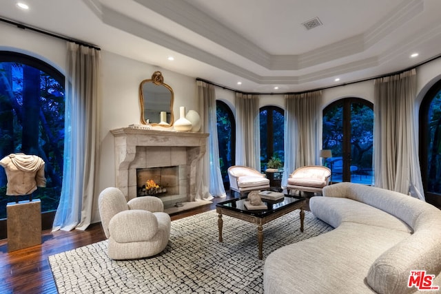 sitting room with french doors, ornamental molding, a raised ceiling, hardwood / wood-style flooring, and a high end fireplace