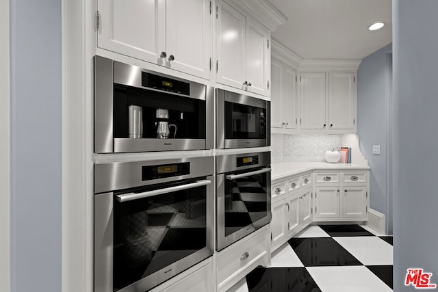 kitchen with built in microwave, stainless steel double oven, white cabinets, and decorative backsplash