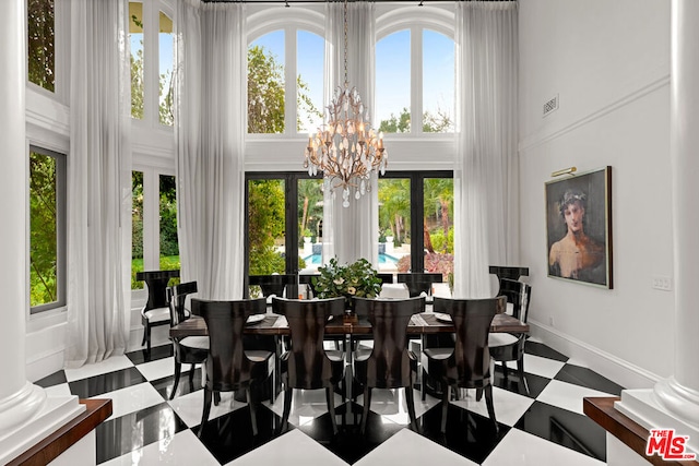 dining area featuring an inviting chandelier, ornate columns, and a high ceiling