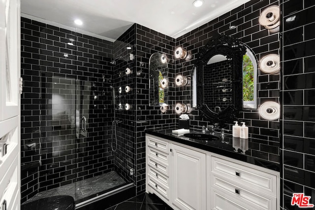 bathroom with vanity, tile walls, and a shower with shower door