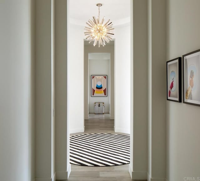 hall with an inviting chandelier and light hardwood / wood-style flooring