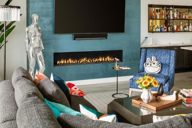 living room featuring bar, hardwood / wood-style flooring, and a large fireplace