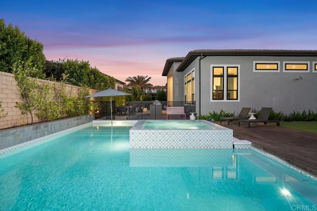 pool at dusk with an in ground hot tub