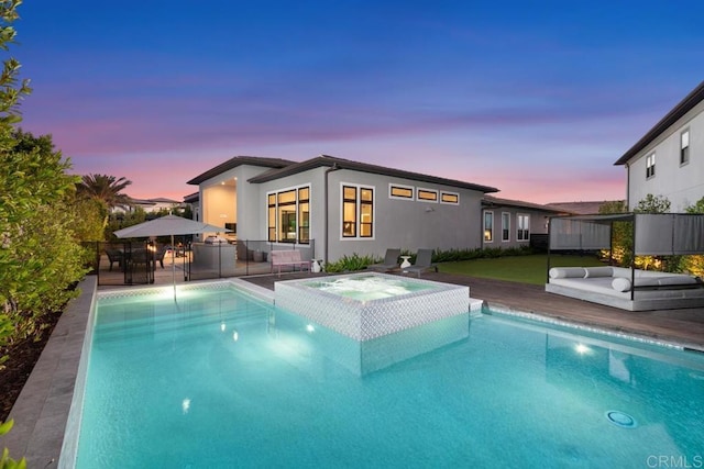 pool at dusk featuring an in ground hot tub