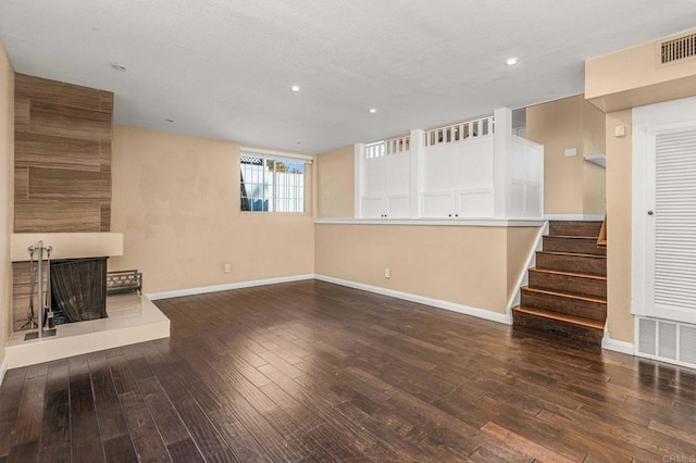 unfurnished living room featuring a multi sided fireplace and dark wood-type flooring