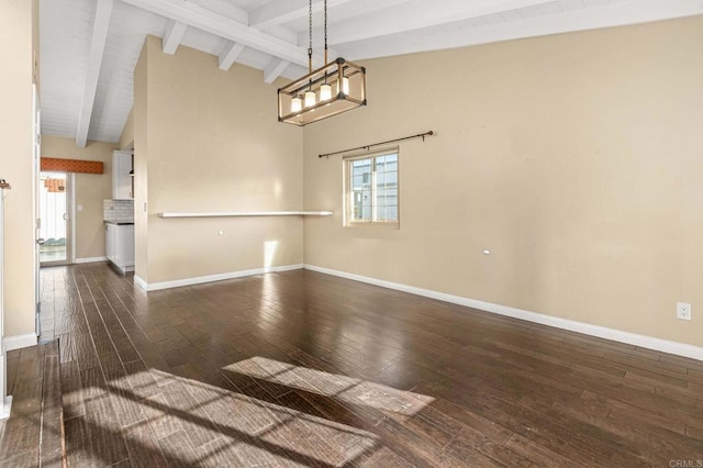 spare room featuring vaulted ceiling with beams and dark wood-type flooring